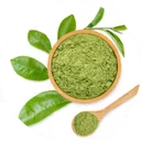 Vivid green matcha powder mounded in a small wooden bowl, bamboo scoop alongside