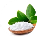 White powdered stevia in a small wooden dish with a couple of leaves at the side